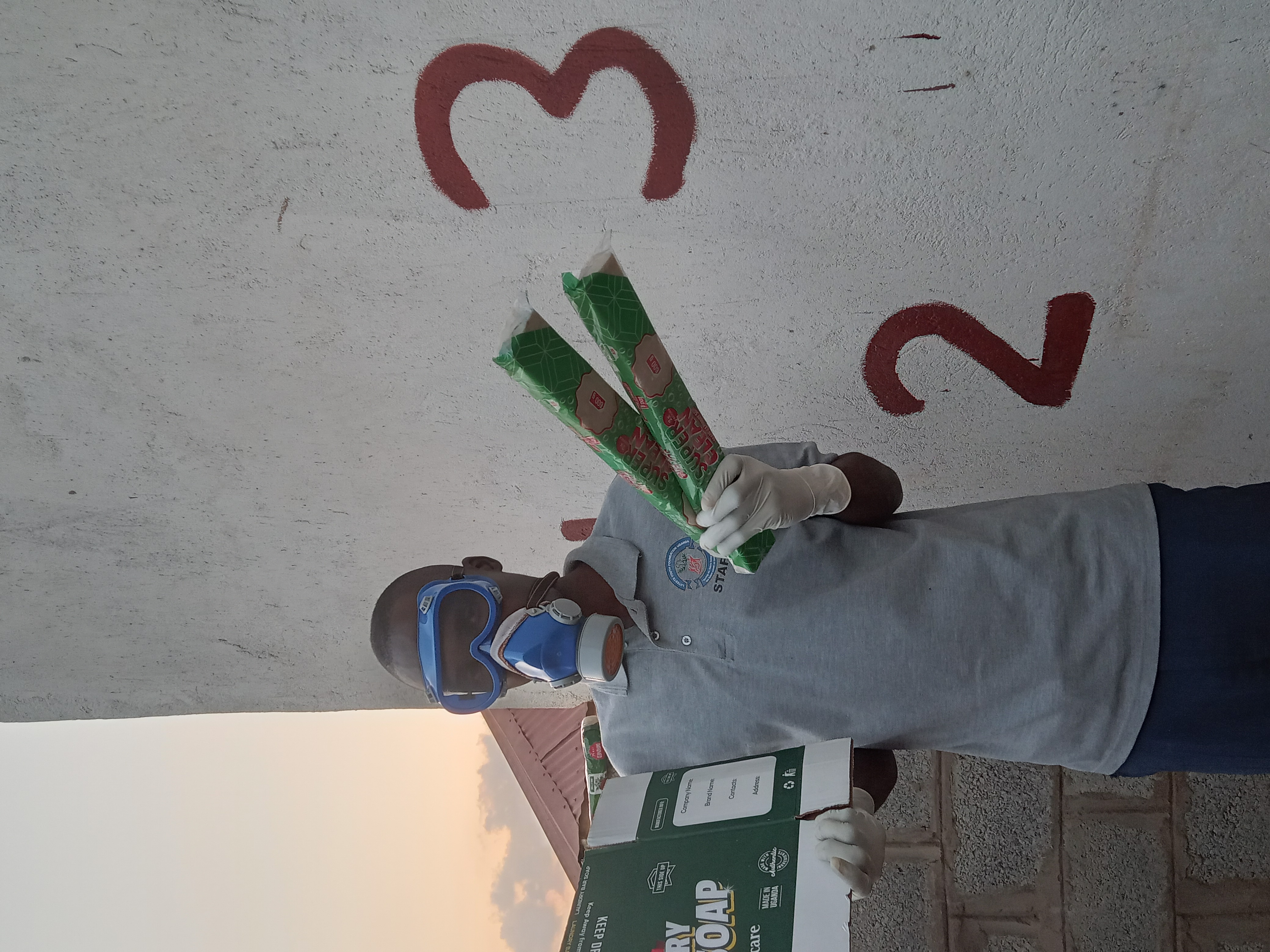 L Y F UGANDA staff member wearing protective gear making laundry soap and packaging at Luteete Youth Foundation Uganda